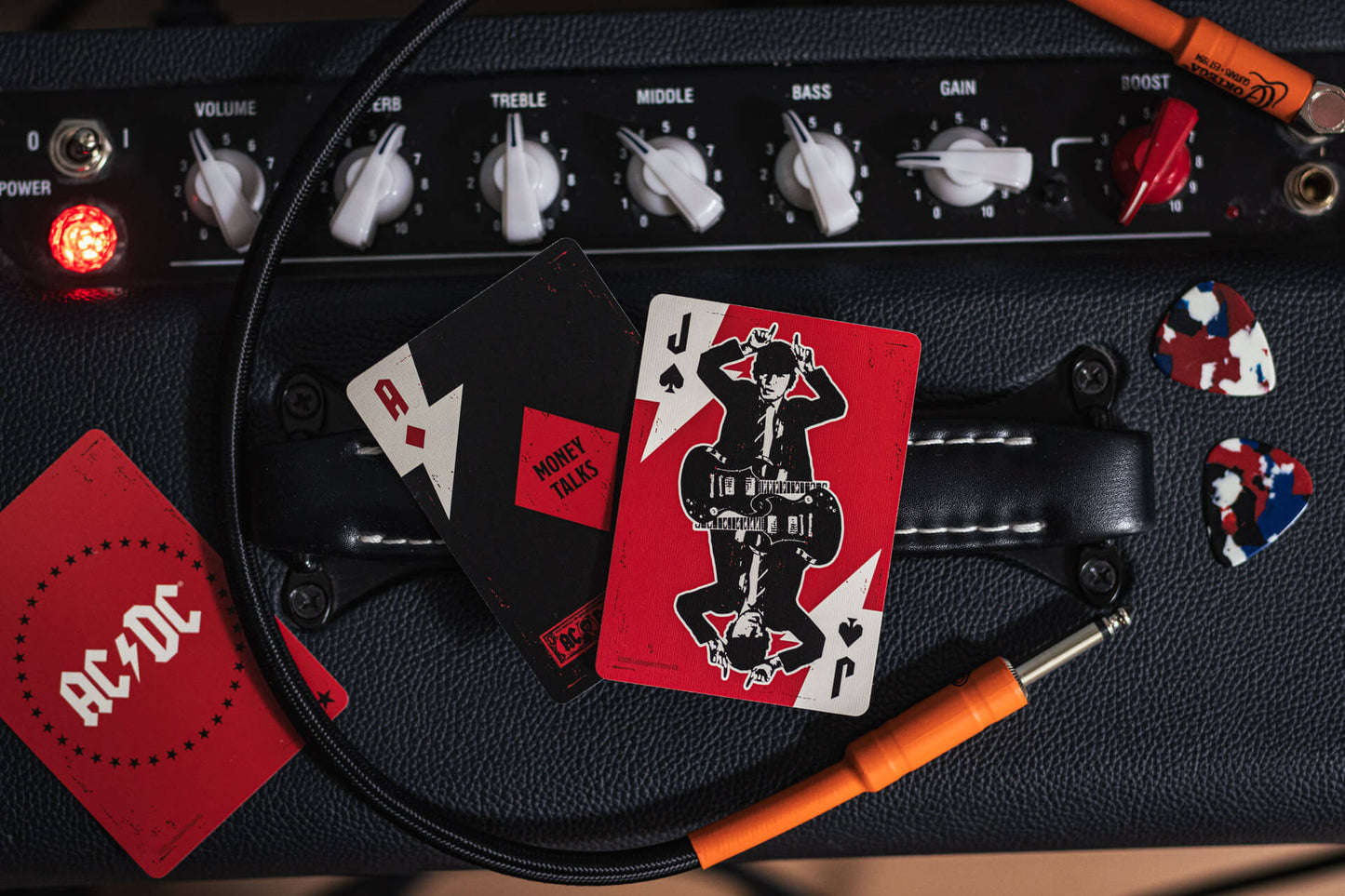 Music amplifier with playing cards and AC/DC logo on a wooden surface