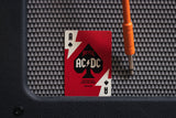 AC/DC playing card on a guitar amplifier with a screwdriver.