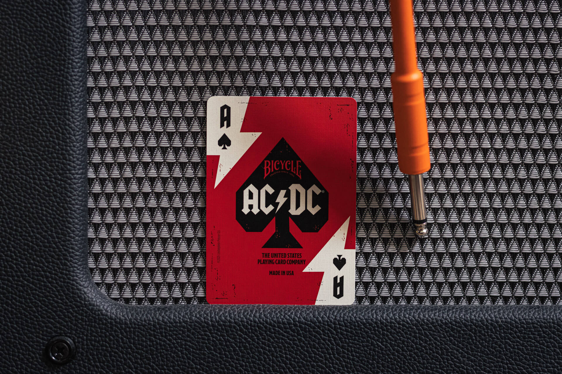 AC/DC playing card on a guitar amplifier with a screwdriver.