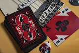 Guitar with AC/DC logo, playing cards, and a guitar pick on a yellow background