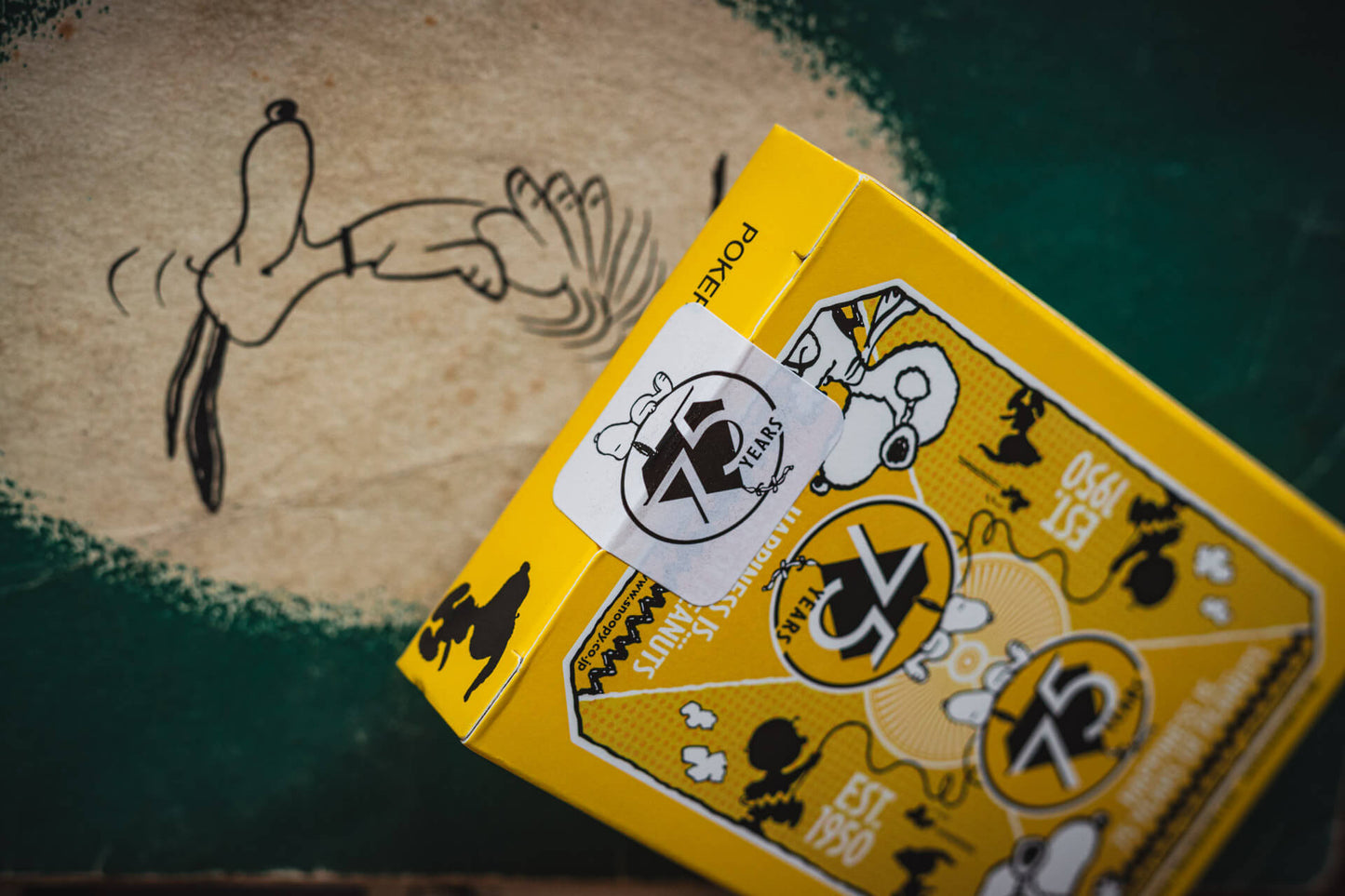 Yellow playing card box with cartoon character on a green surface