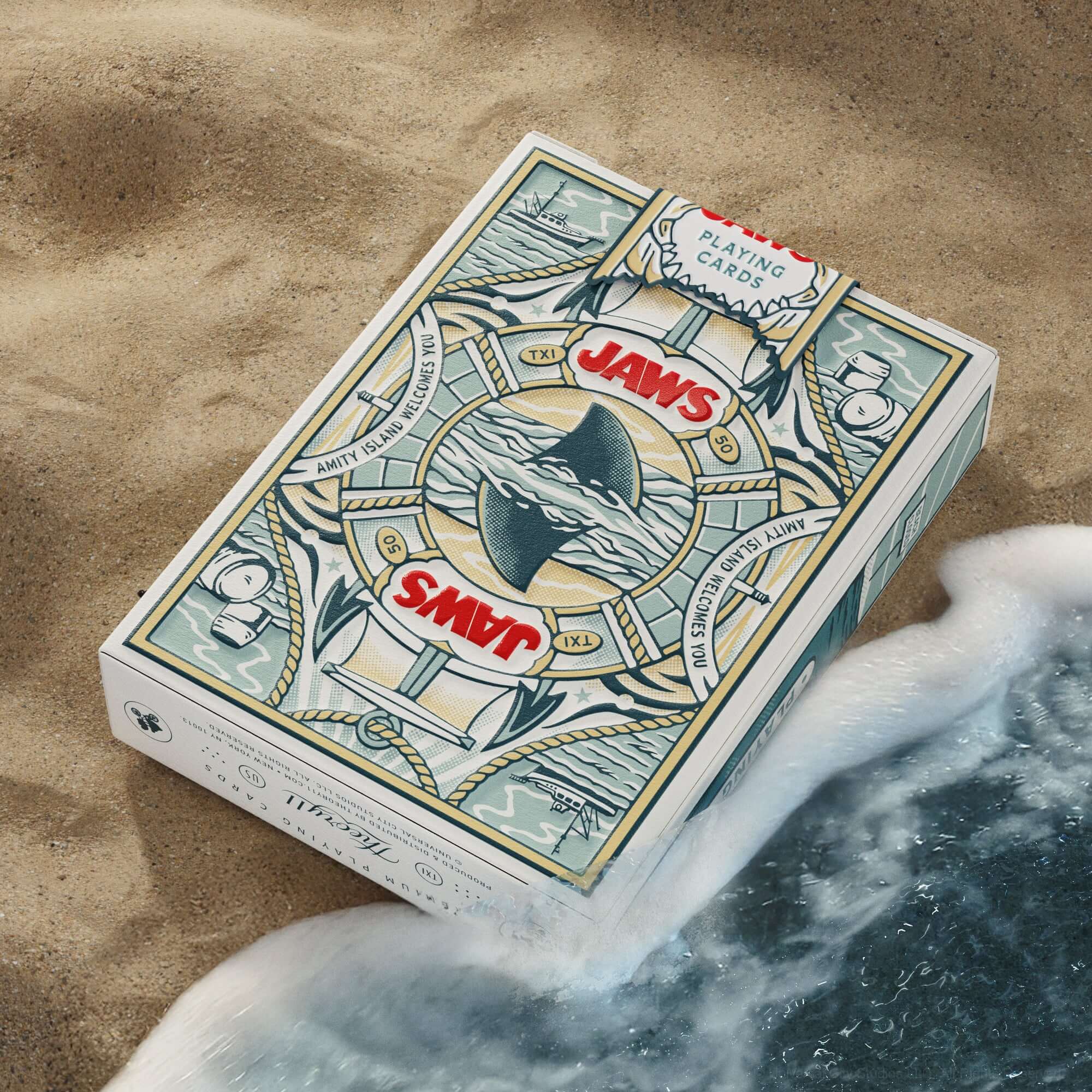Jaws-themed playing cards on a sandy surface with ocean waves.