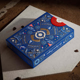 Blue packaging box with intricate designs and branding on a textured surface